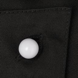 A black fabric close-up featuring a white button, showcasing a clothing accessory in a textured finish.