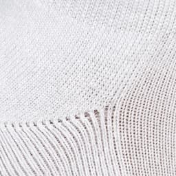 A close-up of a textured white fabric, featuring a knit pattern with visible stitch details.