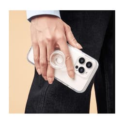 A hand holds a smartphone with a clear, circular PopSocket attached. The phone has a light-coloured case.