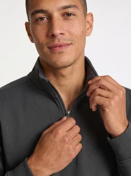A grey and a navy half zip fleece jumper are worn by a woman and a man, standing together outdoors with greenery in the background.