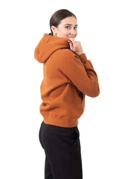 A woman wearing an orange kangaroo pocket hoodie, featuring a hood and a relaxed fit, paired with black pants.