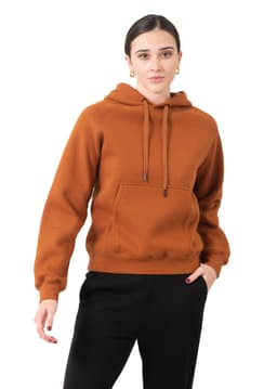 A woman smiles while wearing a burnt orange cotton hoodie with a kangaroo pocket and a logo.