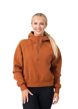 A woman wearing an orange half-zip cotton jumper with a hood, featuring a logo on the front.