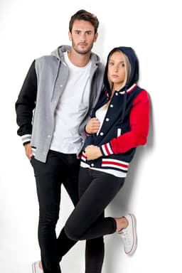 A women's varsity jacket in navy, red, and white, featuring a hood, paired with a grey jacket on a model.
