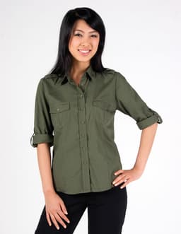 A woman models an olive green women's military long sleeve button-up shirt with rolled sleeves and two chest pockets.