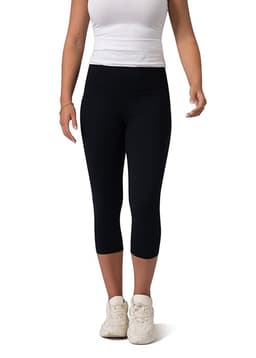 Black high-rise 3/4 leggings worn by a model, paired with a fitted white top and white sneakers.