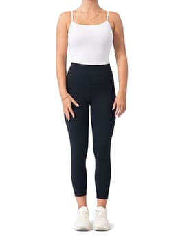 High-rise full-length leggings in black, paired with a white tank top and white sneakers. The model is standing upright.