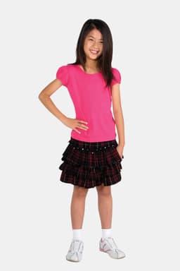 A girl is wearing a pink short puff sleeve T-shirt paired with a black plaid skirt and white shoes.