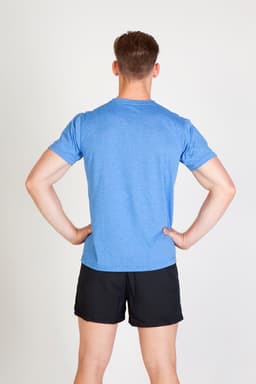 A man wearing a blue heather t-shirt and black shorts, standing with his hands on his hips.