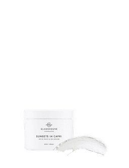 A white jar of body cream with a smooth, creamy texture beside it. The product scent includes white peach and sea breeze.