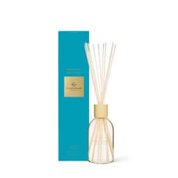 A diffuser featuring a clear glass bottle with wooden reeds, accompanied by a teal box. 