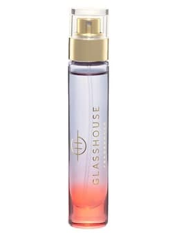 A glass bottle of eau de parfum featuring an ombre design in purple and pink, with a gold spray nozzle and a logo.