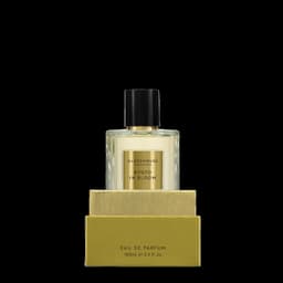A glass perfume bottle filled with a light yellow fragrance, displayed with a gold box. The product features a logo.