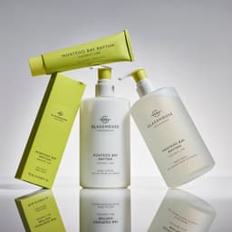 A hand cream and body wash in white bottles with green accents, featuring a branding logo and a matching packaging box.