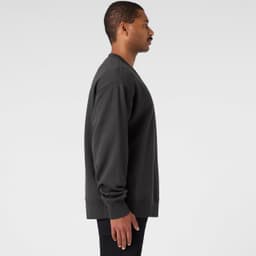 A dark grey jumper featuring a simple design, displayed on a model from the side. The jumper has a logo on it.