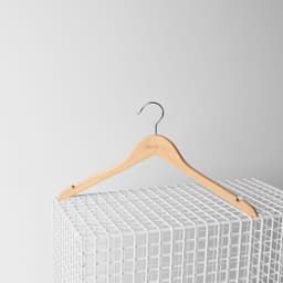 A wooden hanger with a silver hook, featuring a logo, resting on a white wire grid.