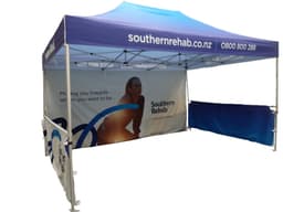 A promotional marquee tent with a blue canopy and printed sidewalls featuring a logo and graphics.