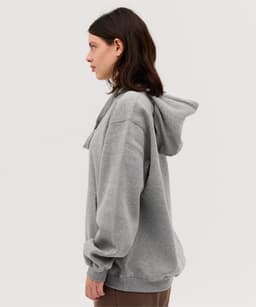 A grey hoodie with a spacious fit and an adjustable hood, featuring a logo on the front.