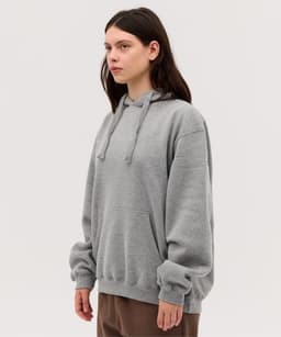 A grey hoodie with a loose fit, featuring a kangaroo pocket and a drawstring hood. It has a logo on the front.