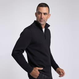 A man wearing a black zippered sweater, standing in profile against a neutral background. The sweater has a sleek, modern design.