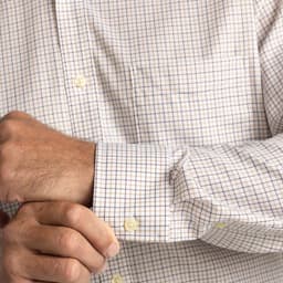 A button-up shirt featuring a check pattern in white, blue, and tan, with a pocket and cuffed sleeves.