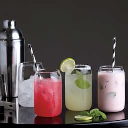 A selection of mixed drinks in glassware, featuring vibrant colours and garnishes, with a cocktail shaker in the background.