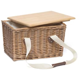 A wicker picnic basket with a wooden lid and a cream-coloured strap for carrying. It has a branded logo.