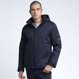 A man wearing a navy soft shell jacket with a hood, featuring zippered pockets and a logo on the sleeve.