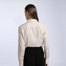 A women's button-up shirt in a cream and brown check pattern, featuring a collar and long sleeves.