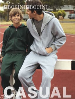 A grey fleece hoodie is worn by one person, seated next to another in a green fleece hoodie, on a sports field.