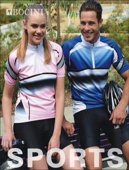 A pair of cyclists in pink and blue cycling jerseys and black shorts, posing with helmets on a park bench.
