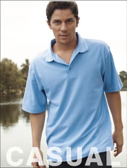 A light blue unisex polo shirt with a collar, being worn by a model outdoors near water.