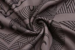 A close-up of a patterned fabric featuring intricate black designs on a grey background.