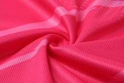 A close-up of a fabric in a vibrant pink colour, featuring a textured pattern. The fabric appears lightweight and smooth.
