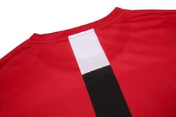 A red uniform t-shirt featuring a white and black vertical stripe on the back, with a logo present.