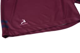 A maroon sports shirt featuring a logo and blue stripes along the hem.