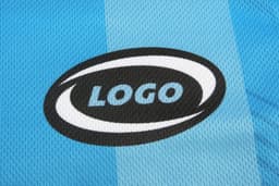A blue sports uniform featuring a logo on a textured fabric. The uniform has a striped design.