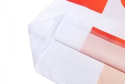 A close-up of a white sports uniform featuring vibrant orange and peach patterns with neat stitching edges.
