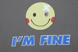 A grey T-shirt featuring a smiley face graphic with a bandage and the text "I'M FINE" in blue.