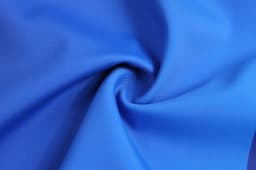 A close-up of smooth, blue fabric arranged in a spiral, showcasing its texture and colour.