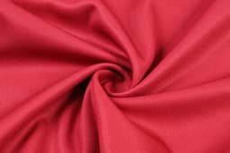 A close-up of red fabric, showcasing a smooth texture with a spiral pattern. The material appears lightweight and breathable.