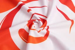 A swirl of vibrant red and orange fabric featuring bold graphic patterns. The material is smooth and lightweight.