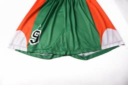 Green and orange junior soccer shorts featuring a black number 9 and curved white accents. Includes a logo.