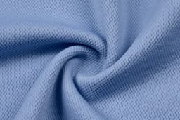 A close-up of light blue textured fabric, displaying a soft, woven pattern suitable for apparel.