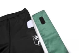 Black shorts with a white patch and a green side panel, featuring a logo.