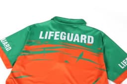 A quarter zip lifeguard uniform in green and orange with a logo on the back and sleeves.