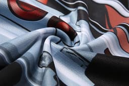 A close-up of a polyester fabric featuring a vibrant design with red, blue, and black elements, including a logo.