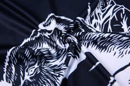 A fabric featuring a swirling design in black and white, showcasing detailed animal motifs.