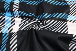 A fabric featuring a blue, black, and white checkered pattern in a swirling arrangement.