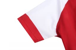 A red and white sports uniform featuring a short sleeve design, with a logo on the fabric.